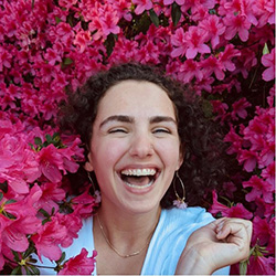 girl sitting in flower bush laughing