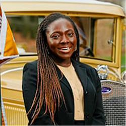 A person standing in front of a yellow car