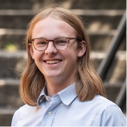 A person with long hair and glasses in a button up shirt